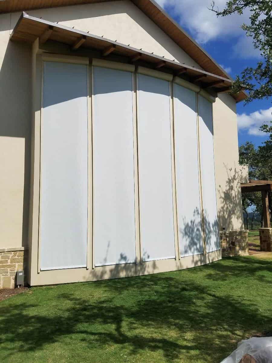 Four vertical outdoor solar screens installed on a large building