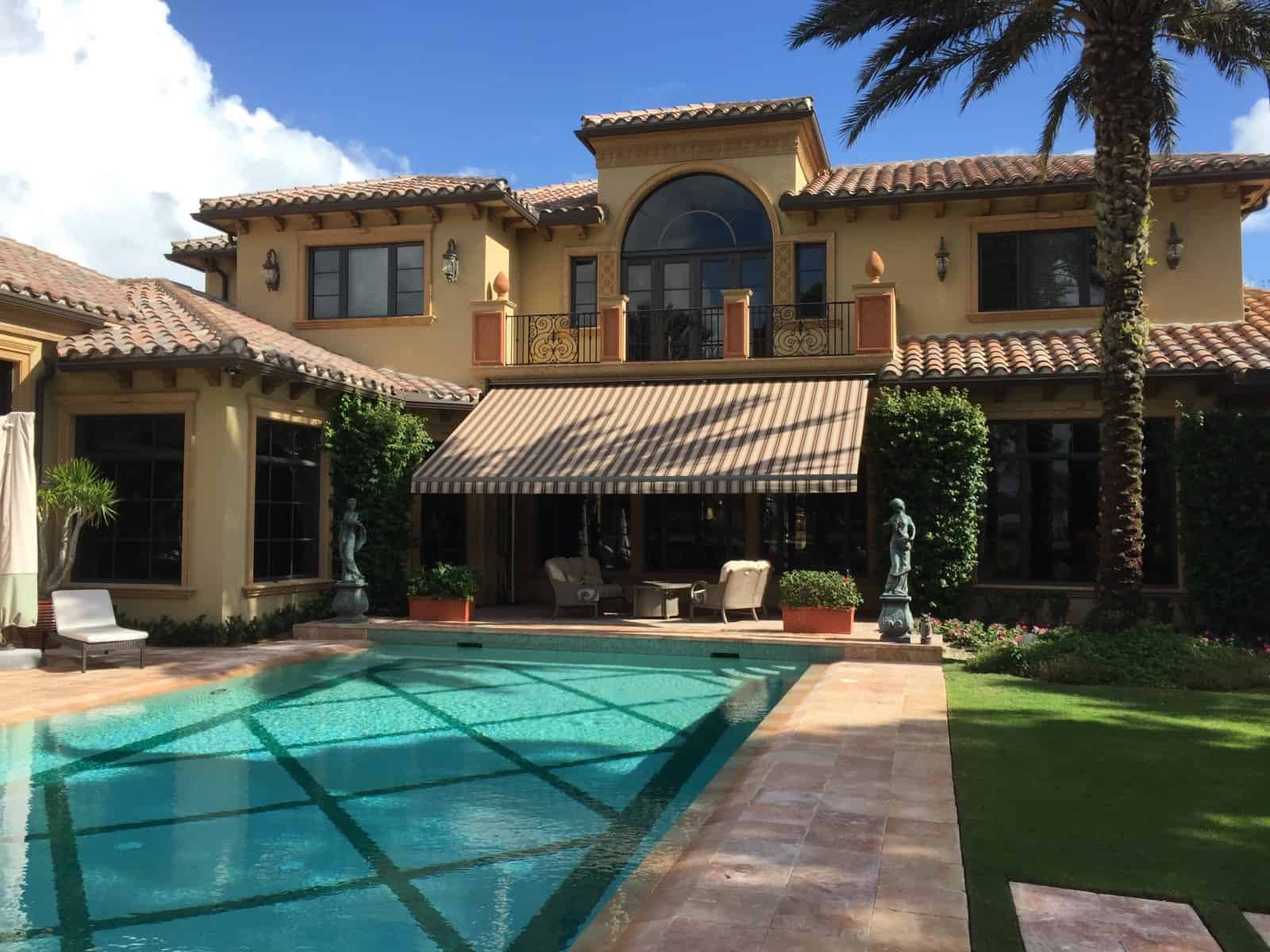 Retractable drop arm awning extended over pool patio