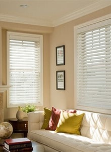 Sunlight shining through opened white blinds in a living room